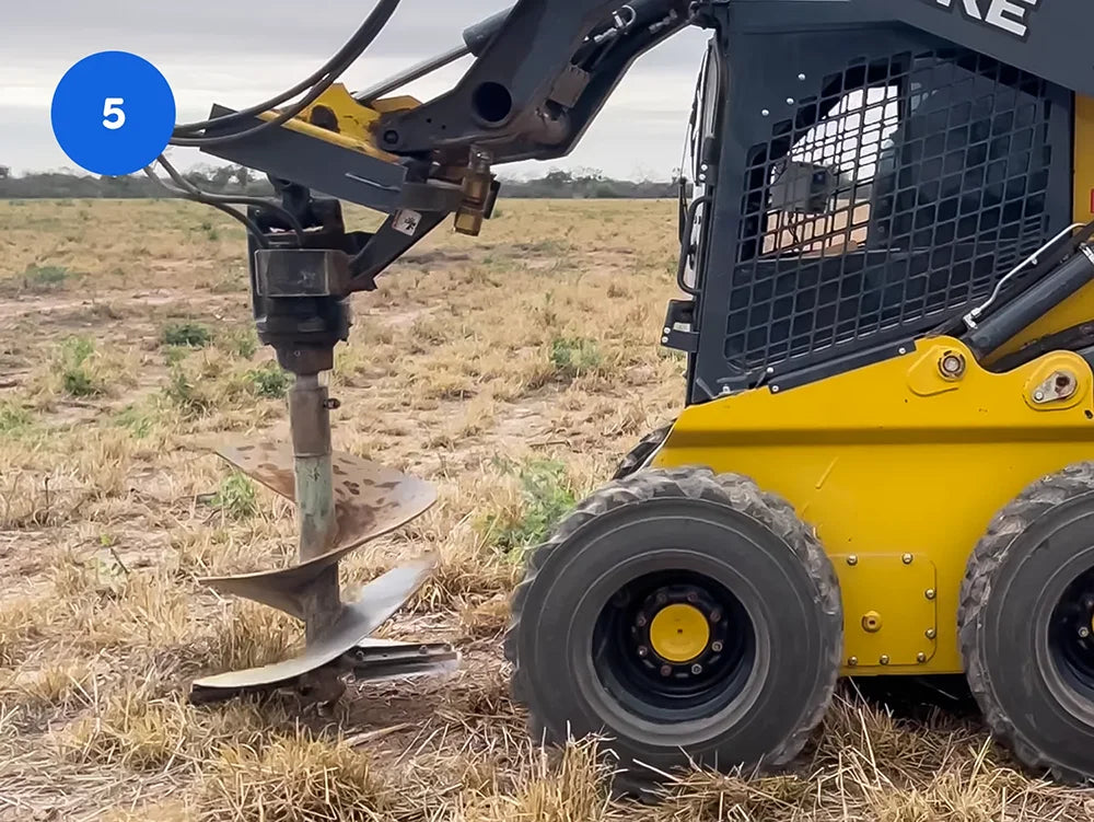 Die landwirtschaftliche Maschine bohrt in das von Gras bewachsene Feld ein Loch mit einem Metall Bohrer.